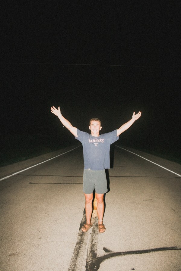 Figure on a road at night with arms raised